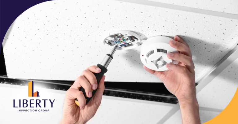 Hands installing or repairing a ceiling-mounted smoke detector using a screwdriver